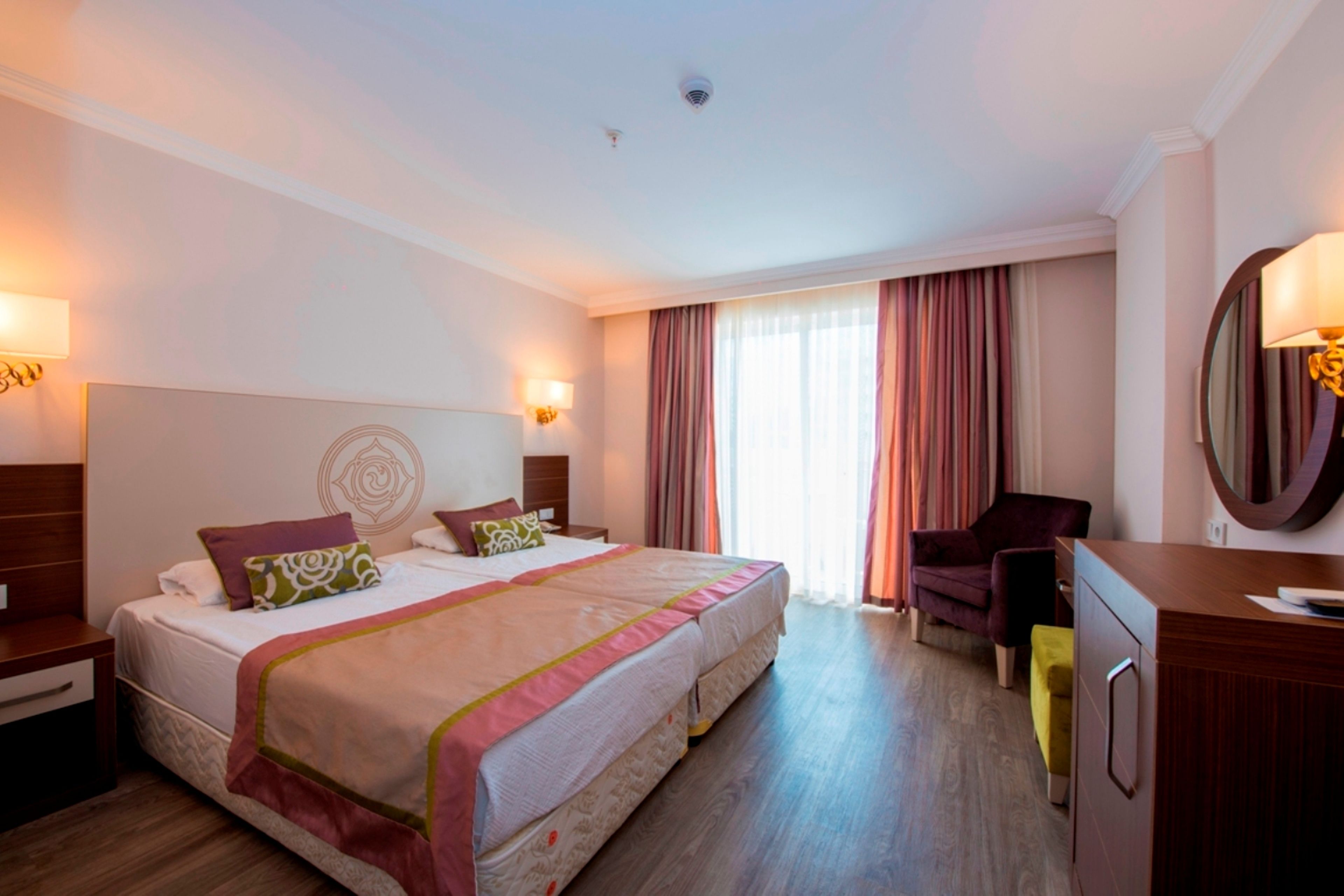 Ein Hotelzimmer mit Doppelbett, Schreibtisch, Stuhl und Spiegel.