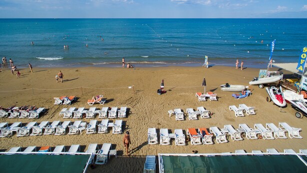 A beach with rows of sun loungers, a lifeguard tower, and a boat. - Side Alegria Hotel & Spa - Adults Only - All inclusive (Manavgat)