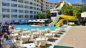 A hotel pool area with multiple slides, outdoor seating, and a large building in the background. - Side Alegria Hotel & Spa - Adults Only - All inclusive (Manavgat)