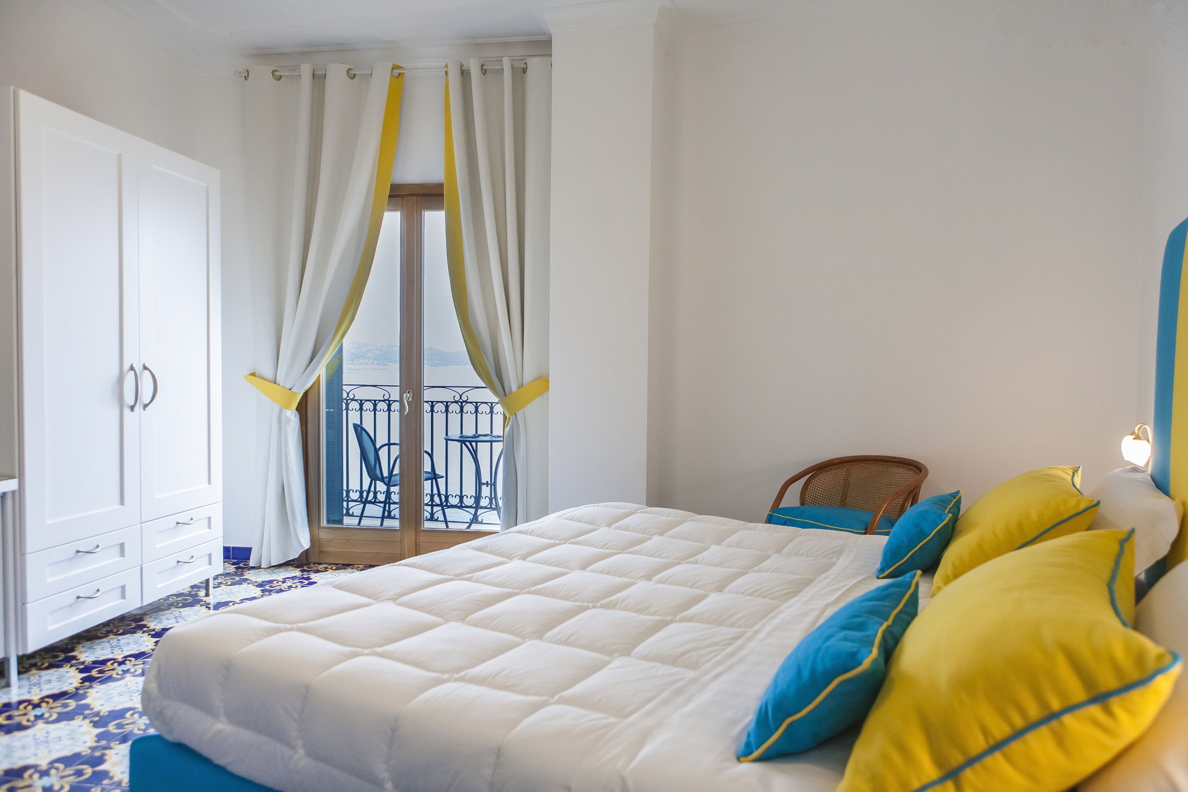 Quarto com cama grande, guarda-roupa, cadeira e varanda com vista.