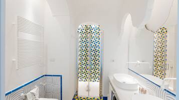 A bathroom with a white sink, a mirror, and a shower with a geometric tile pattern.