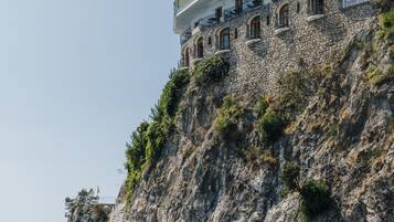 A coastal building with a staircase leading up to a balcony, overlooking the sea.