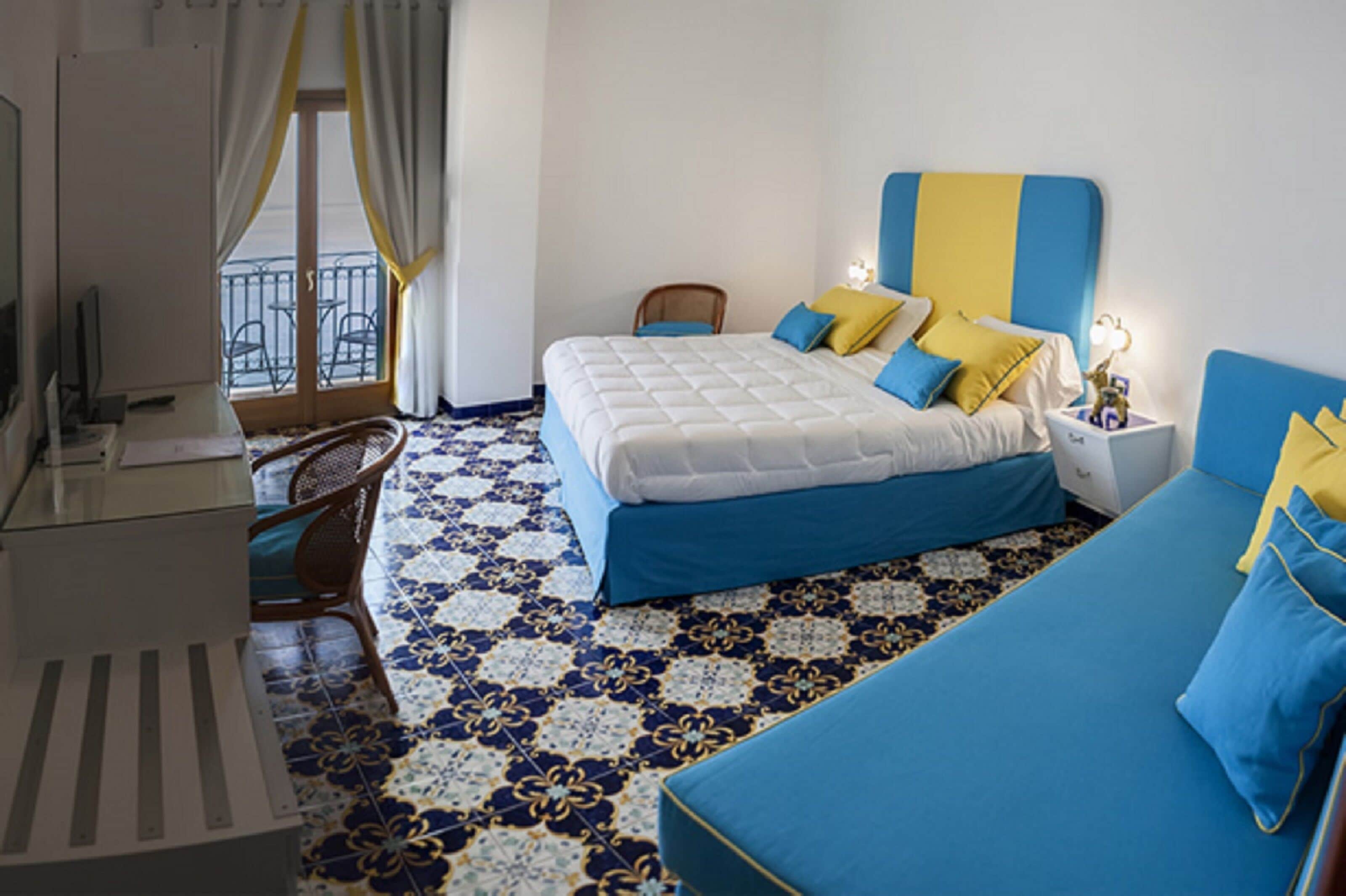 Una camera d'albergo con un letto, una scrivania, una sedia e un balcone con vista.