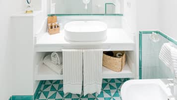 Une salle de bain moderne avec un meuble-lavabo blanc, un grand miroir et un carrelage au motif géométrique.