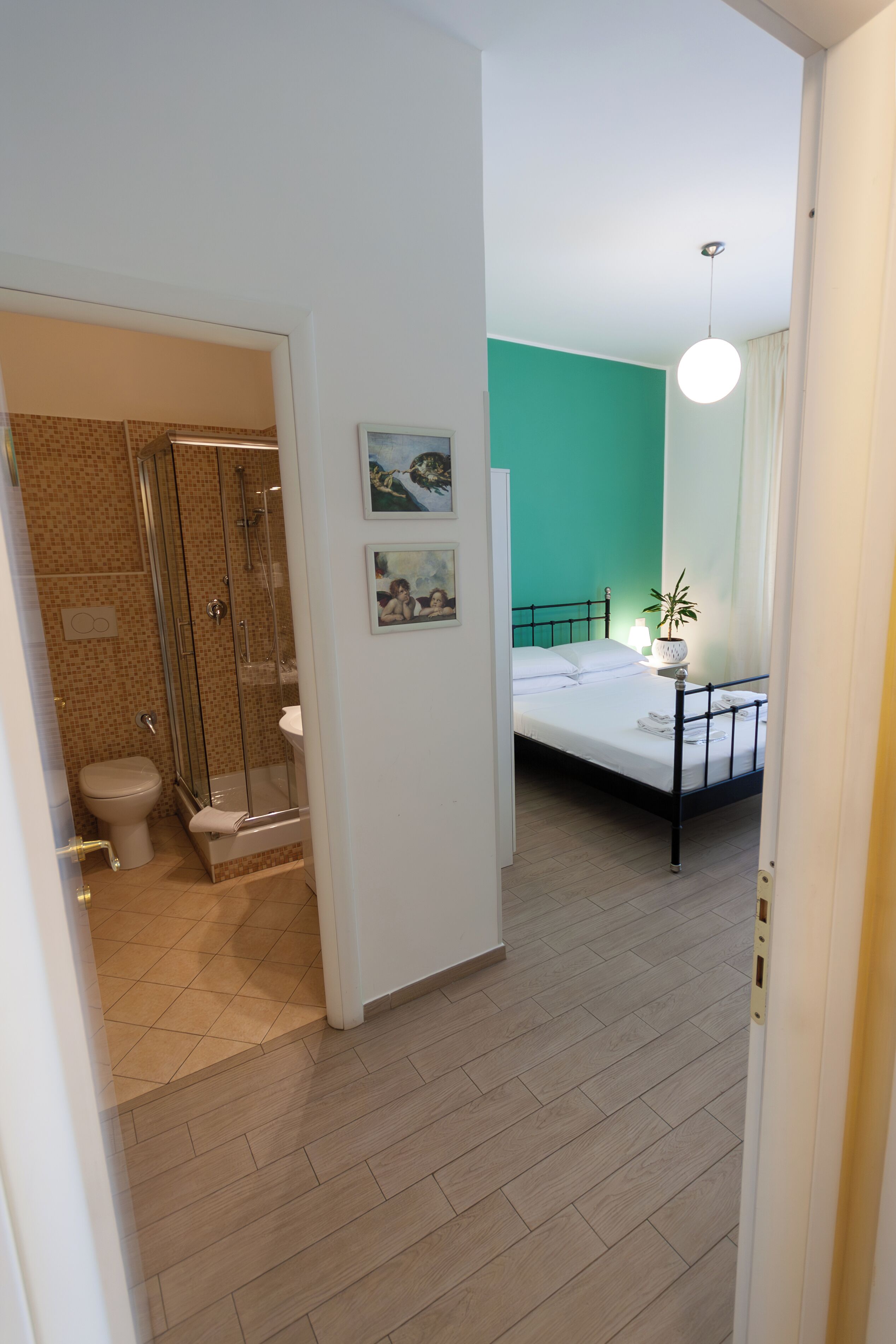 A hotel room with a shower, toilet, bed, and a green wall.