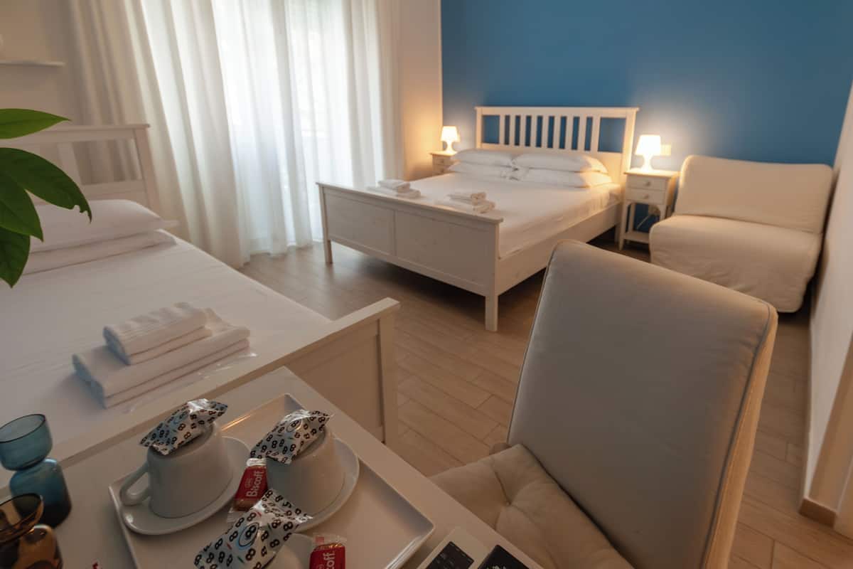 A hotel room with a bed, a chair, a table with a tray of breakfast items, and a window with curtains.