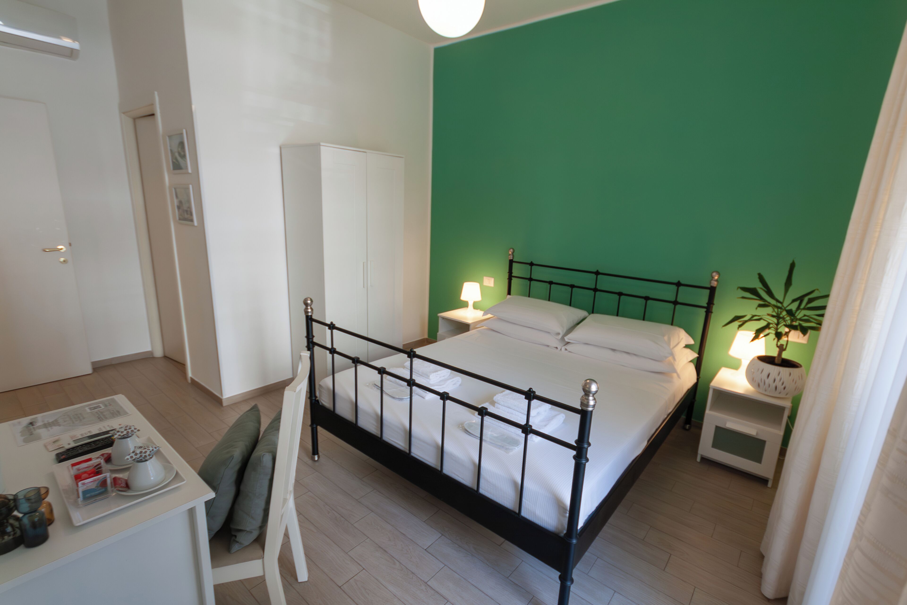 Un dormitorio con cama, mesitas de noche, escritorio y una silla.