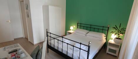 Un dormitorio con cama, mesitas de noche, escritorio y una silla.