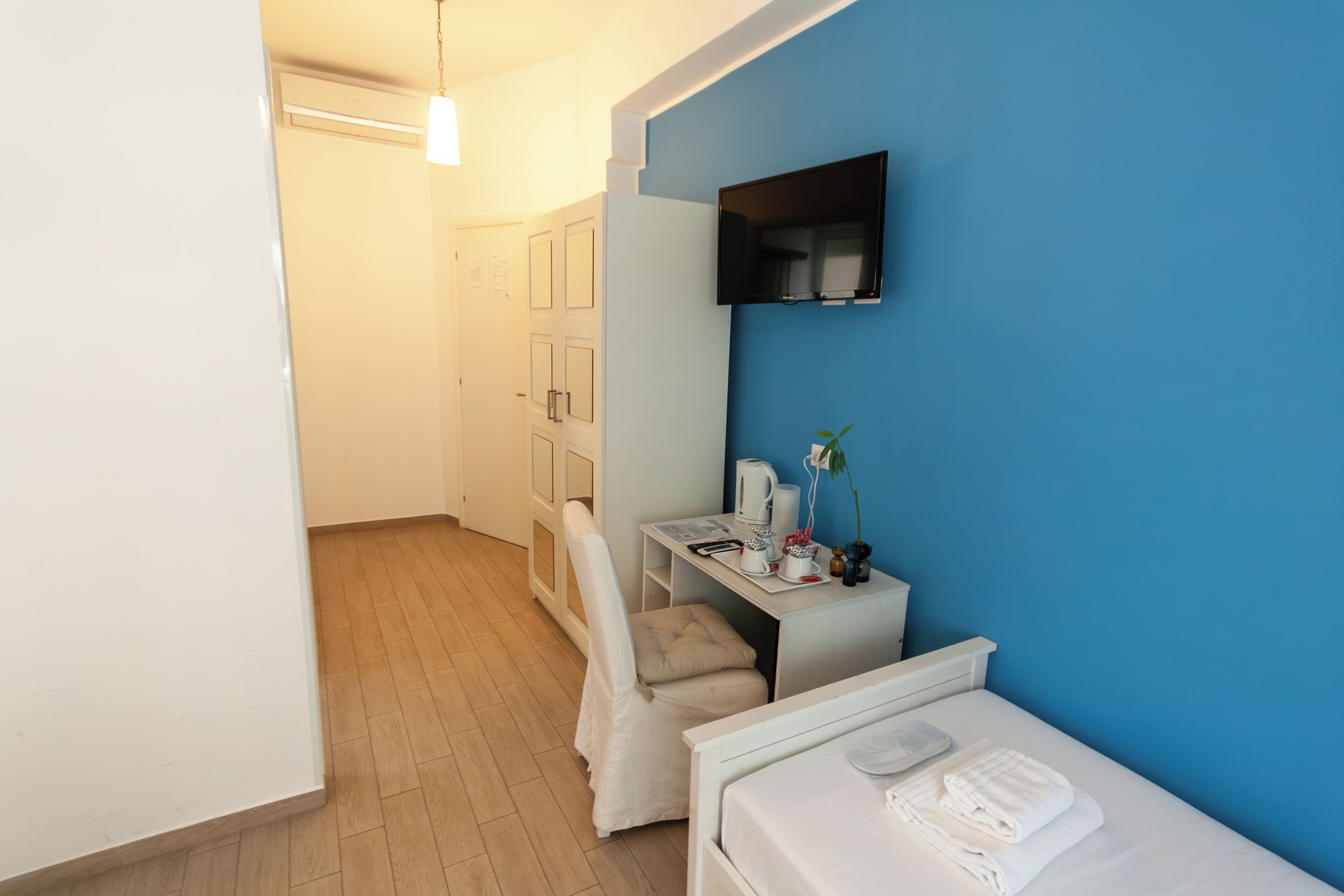 A hotel room with a bed, a desk, a chair, and a TV.