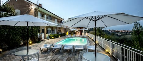 Een buitenzwembad, parasols voor strand/zwembad