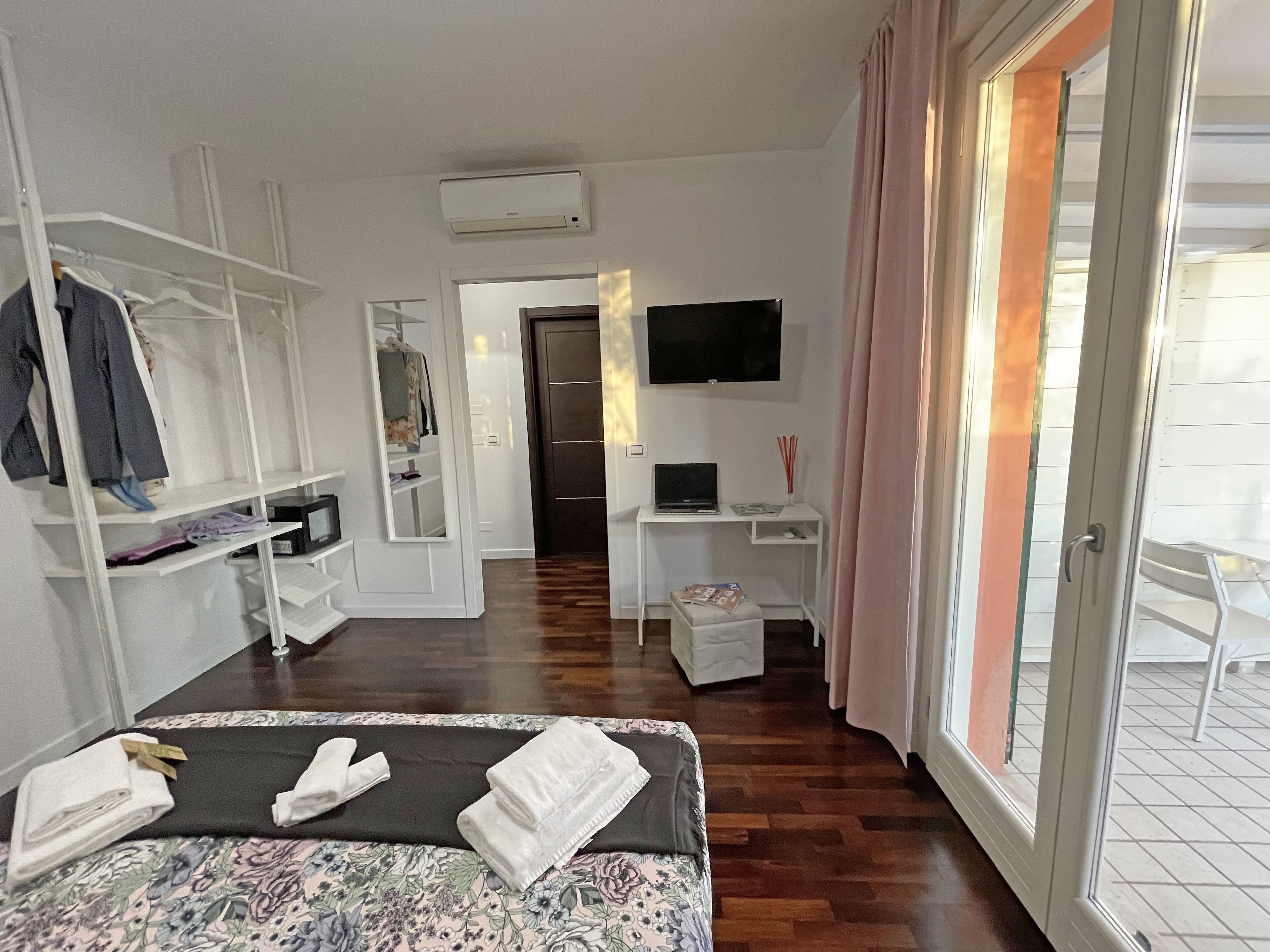 Ein Hotelzimmer mit Bett, Schreibtisch, Fernseher, Kleiderschrank und einem Balkon mit Blick.