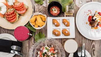 Una mesa de madera con diversos platos, entre ellos, una tostada de aguacate, un tazón de sopa y un plato de postre.