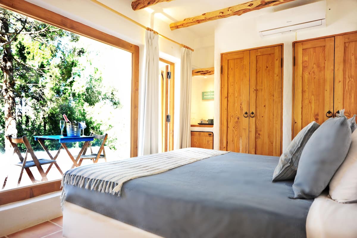 Une chambre avec un grand lit, une armoire en bois et une fenêtre avec des rideaux.