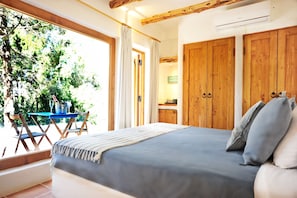 A bedroom with a large bed, wooden wardrobe, and a window with curtains. - Can Vistabella Boutique Resort (Sant Antoni de Portmany)