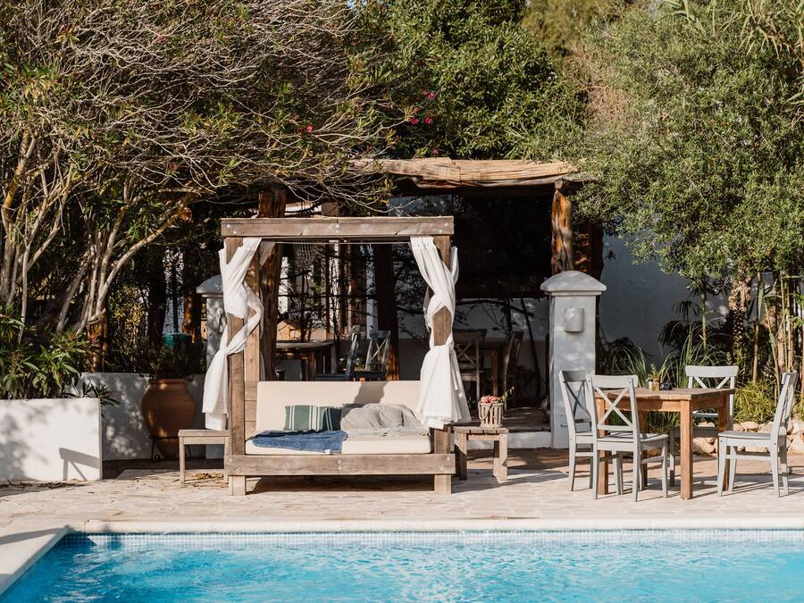 Ein Poolbereich mit einer Holzpergola, Sitzgelegenheiten und Blick auf den Pool.
