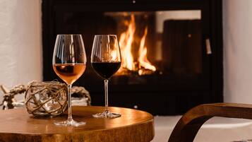 Dos copas de vino sobre una mesa de madera, con una chimenea al fondo.