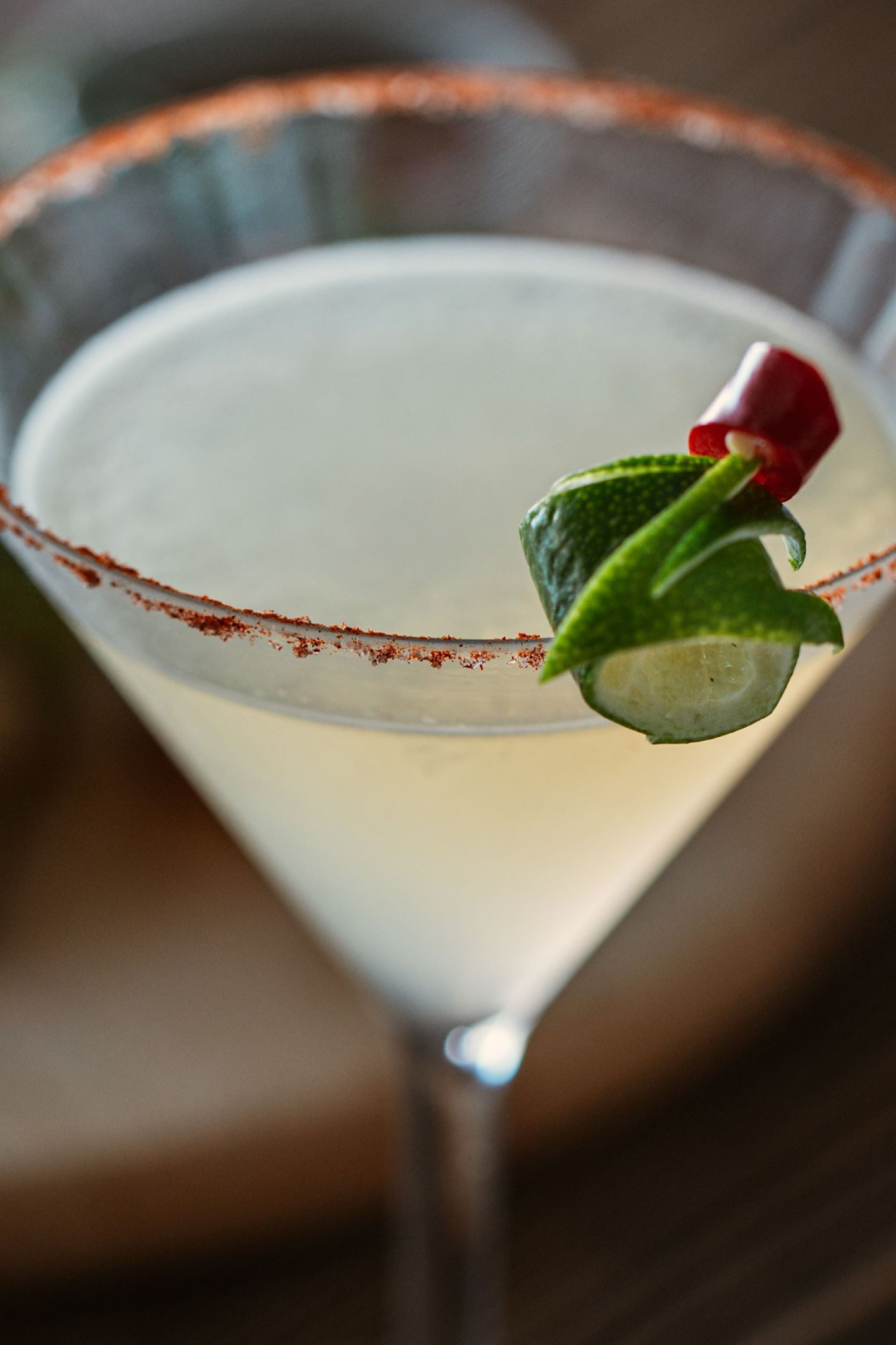 Un vaso de margarita adornado con una rodaja de lima y un chile rojo.