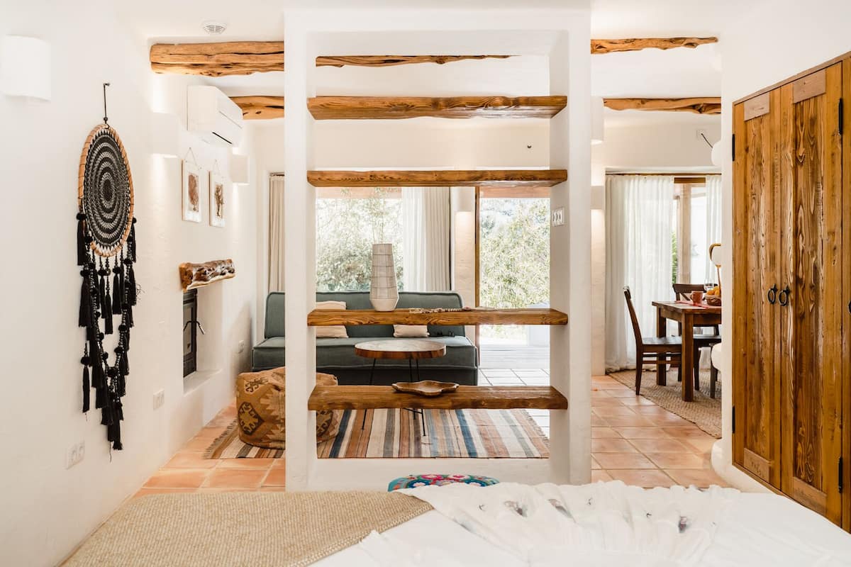 Un intérieur moderne avec des poutres apparentes, un espace salon central comprenant un canapé et une table basse, et un coin repas avec une table et des chaises en bois.