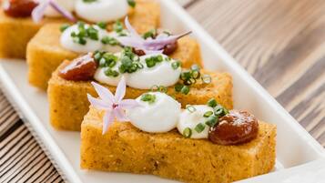 A white rectangular plate with several square pieces of food, garnished with green onions and a flower.