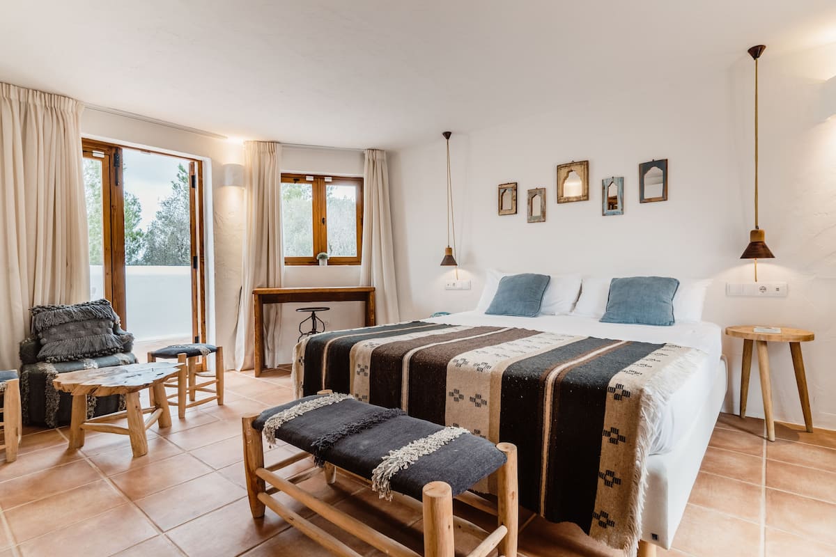 Une chambre à coucher avec un grand lit, un banc en bois, un bureau et une chaise.