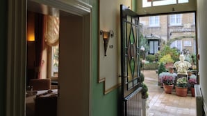 A hotel entrance with a green door, a glass door leading to a courtyard with potted plants and a statue, and a sign reading "HOTEL ROYAL". - Hotel Botticelli (Maastricht)