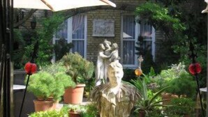 A courtyard with potted plants, a statue, and a large umbrella. - Hotel Botticelli (Maastricht)