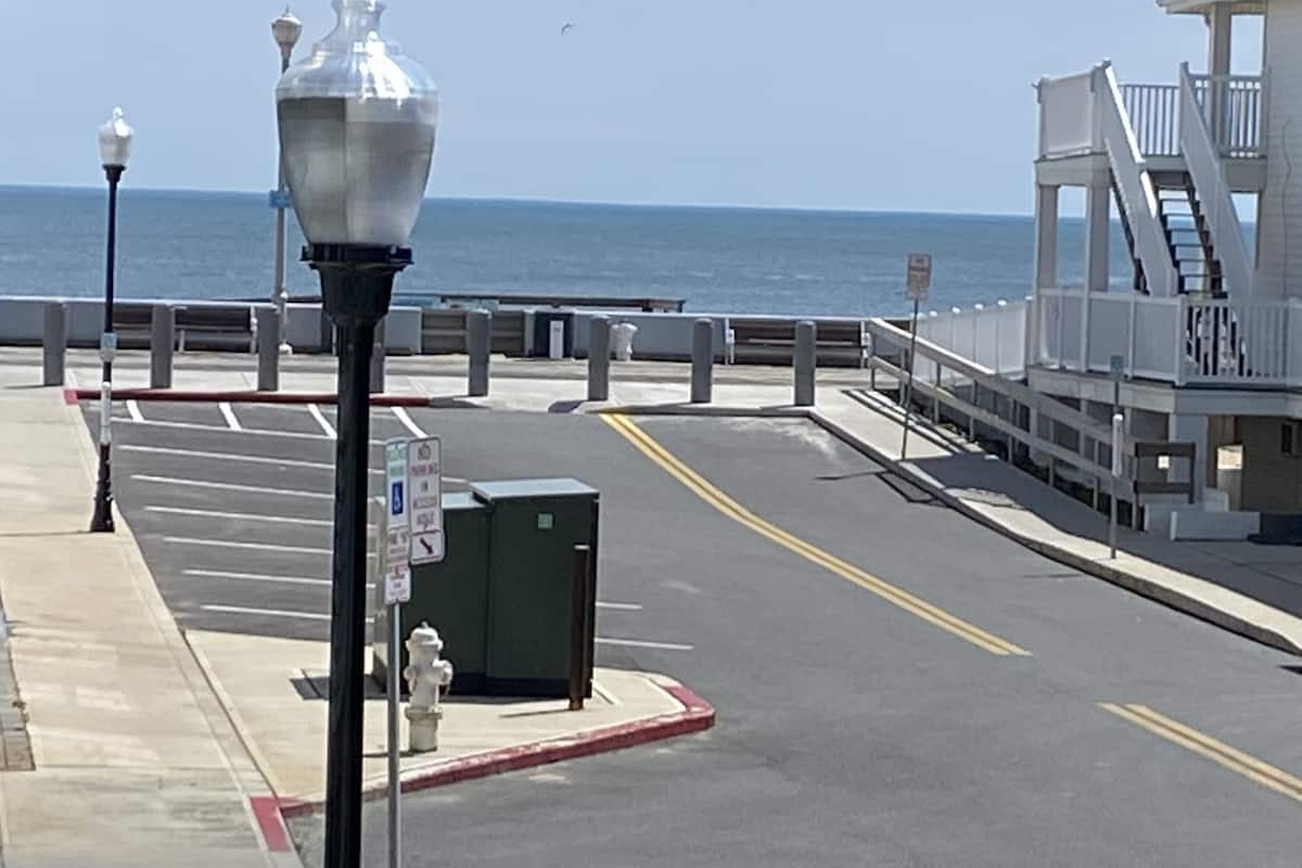 Ein Küstenweg mit einer Straßenlaterne, einem Hydranten und einem Gebäude mit einem Balkon mit Blick auf das Meer.