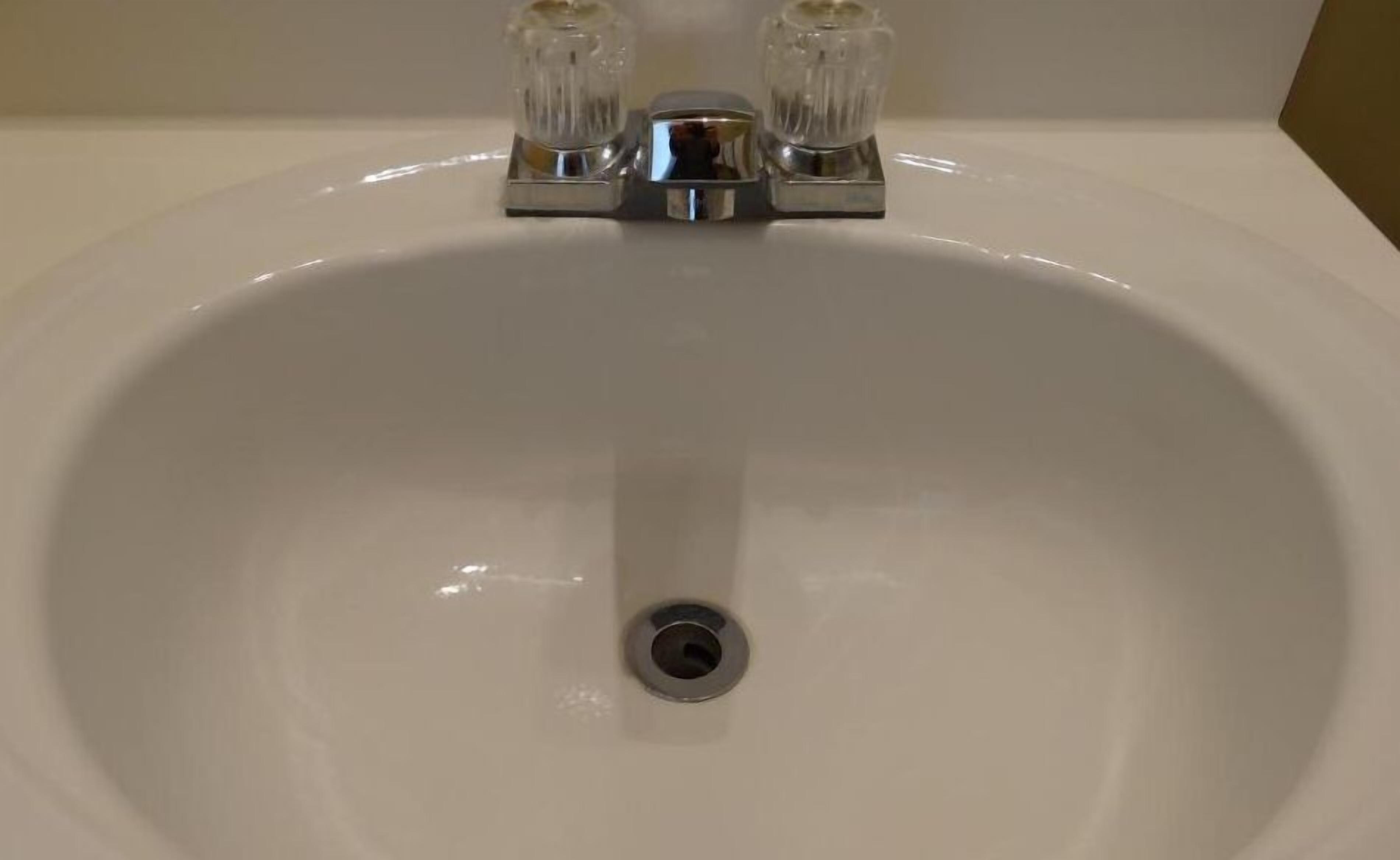 A white bathroom sink with a chrome faucet and a single drain.