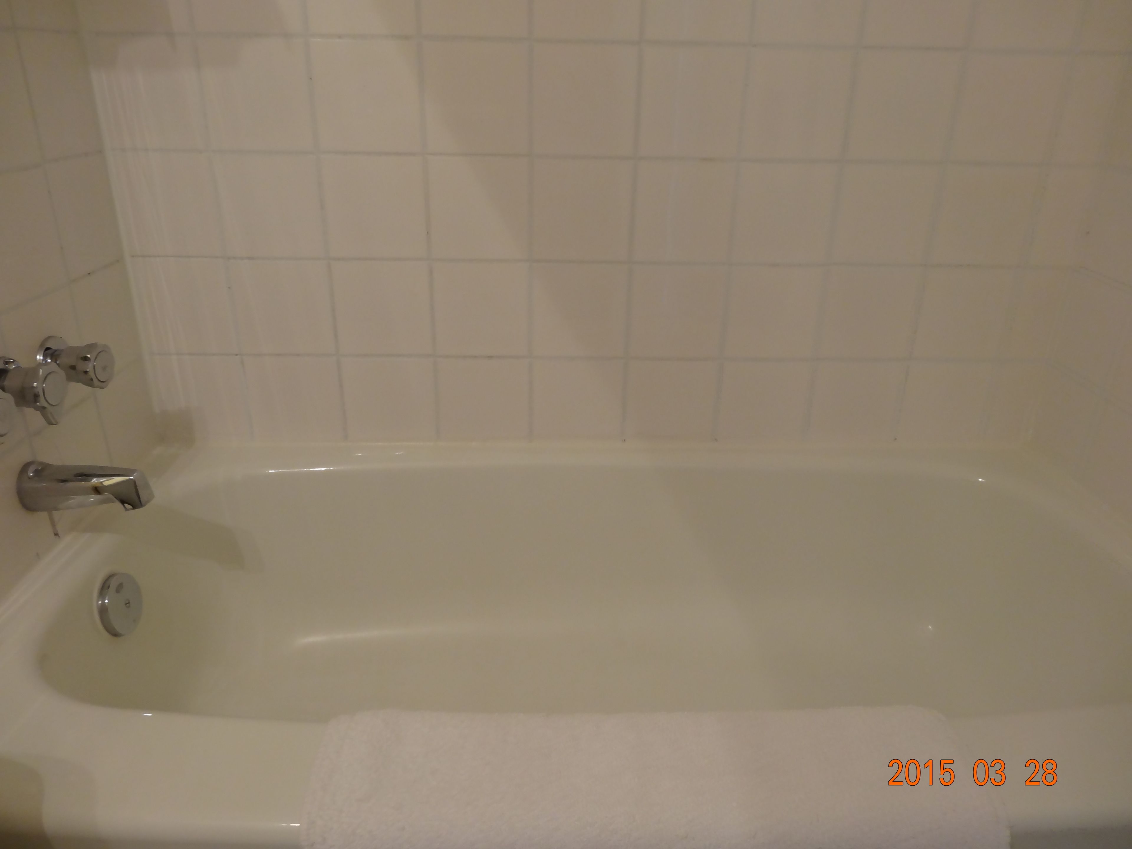 Una bañera estándar con un solo grifo y una toalla sobre el borde.