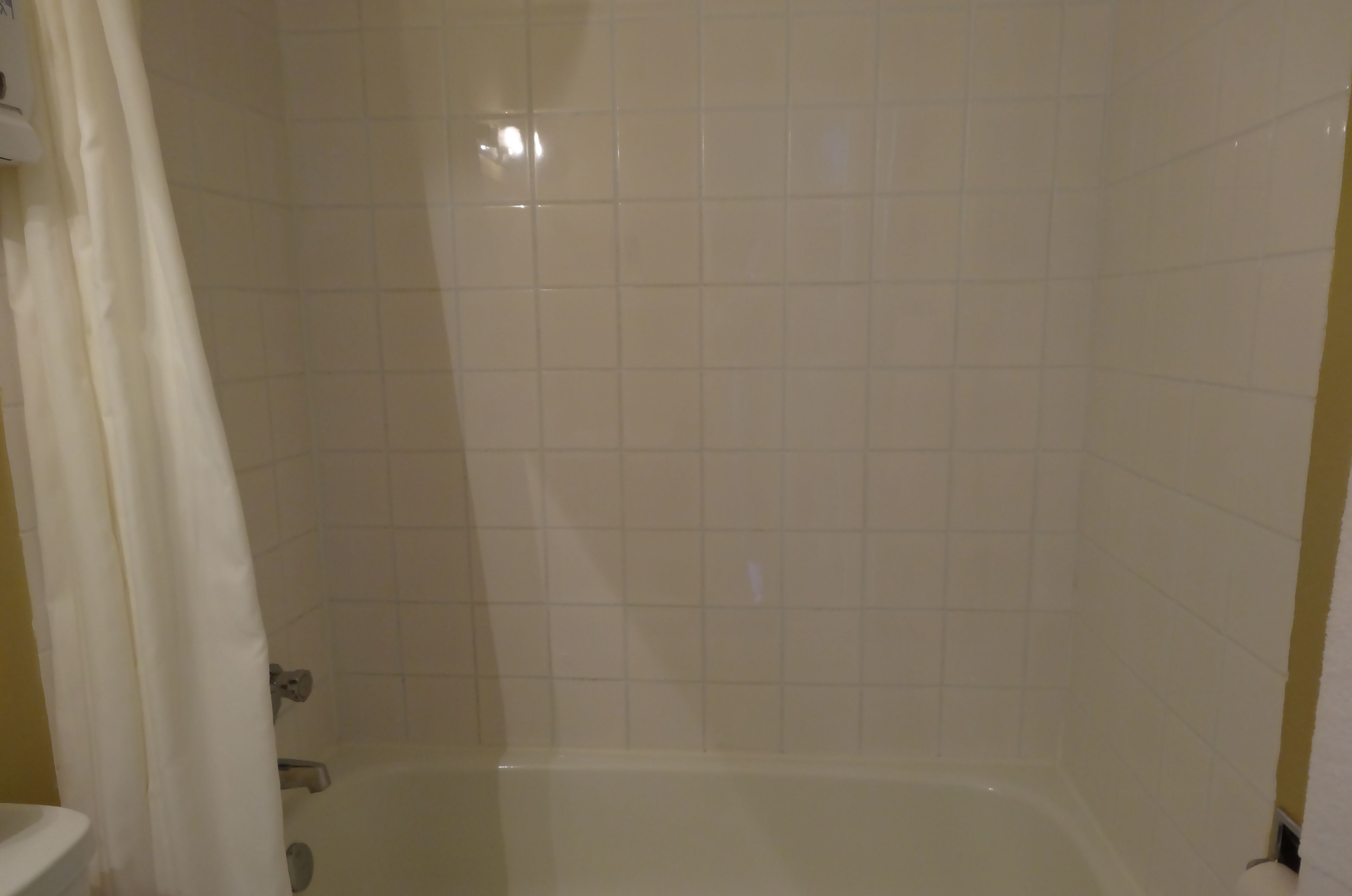 A bathroom with a bathtub, tiled walls, and a shower curtain.