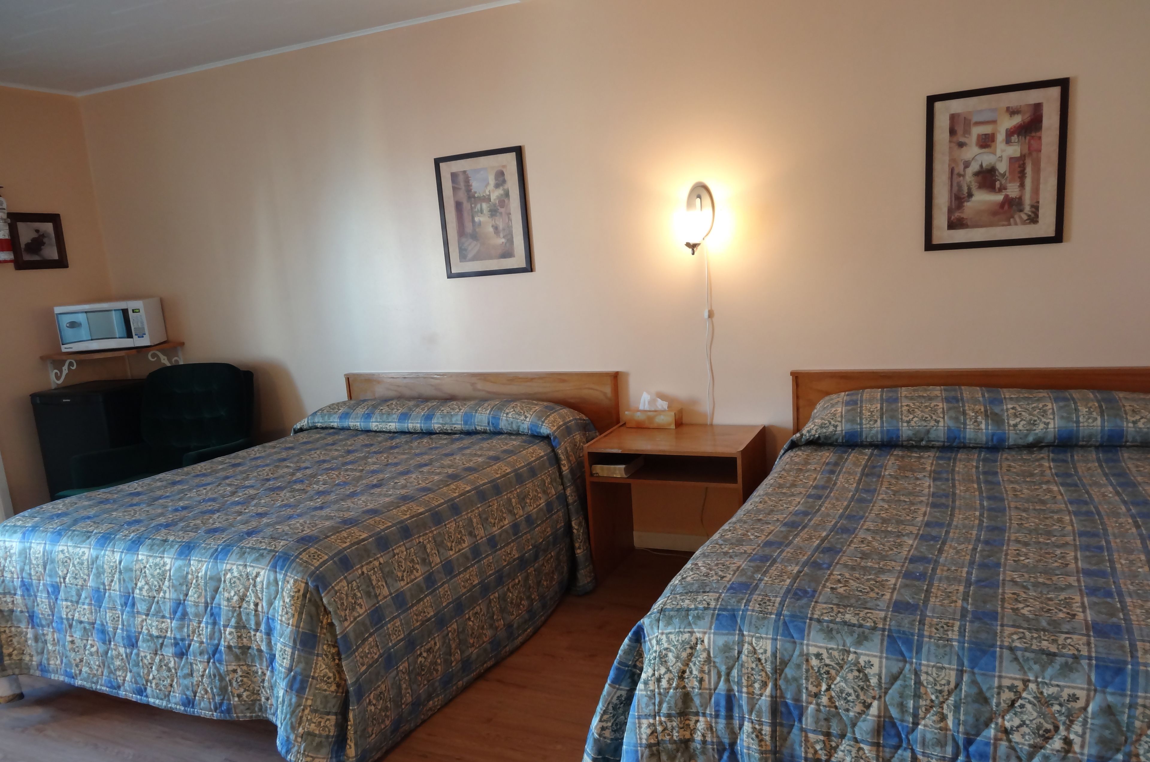 Une chambre d’hôtel avec deux lits, un bureau, une table de chevet, une lampe et un téléviseur.