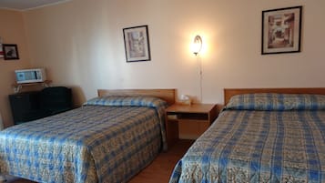 Une chambre d’hôtel avec deux lits, un bureau, une table de chevet, une lampe et un téléviseur.