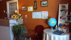 Een kamer met een bureau, stoel, wereldbol en diverse voorwerpen aan de muur.