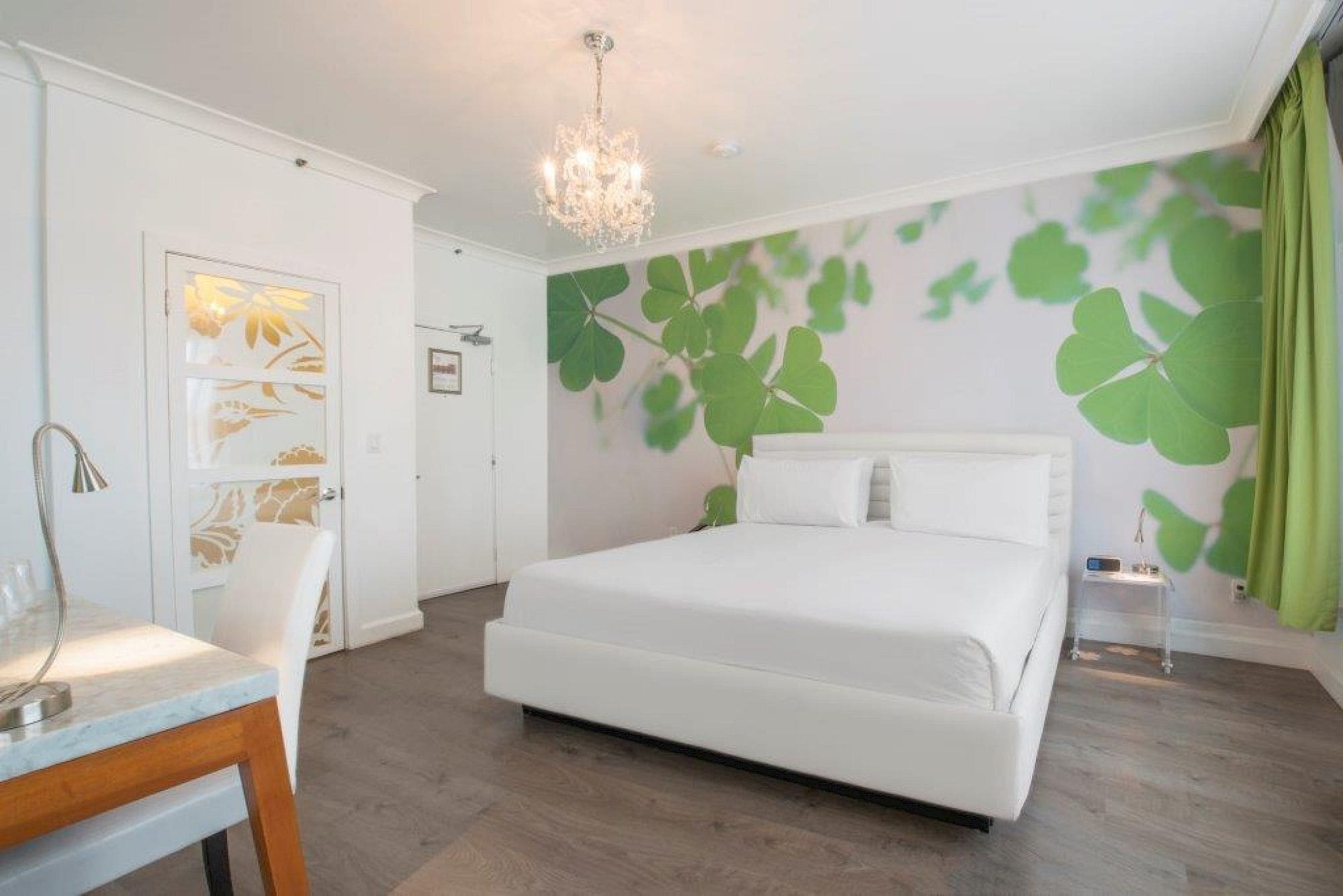 A bedroom with a bed, a desk, and a chandelier.