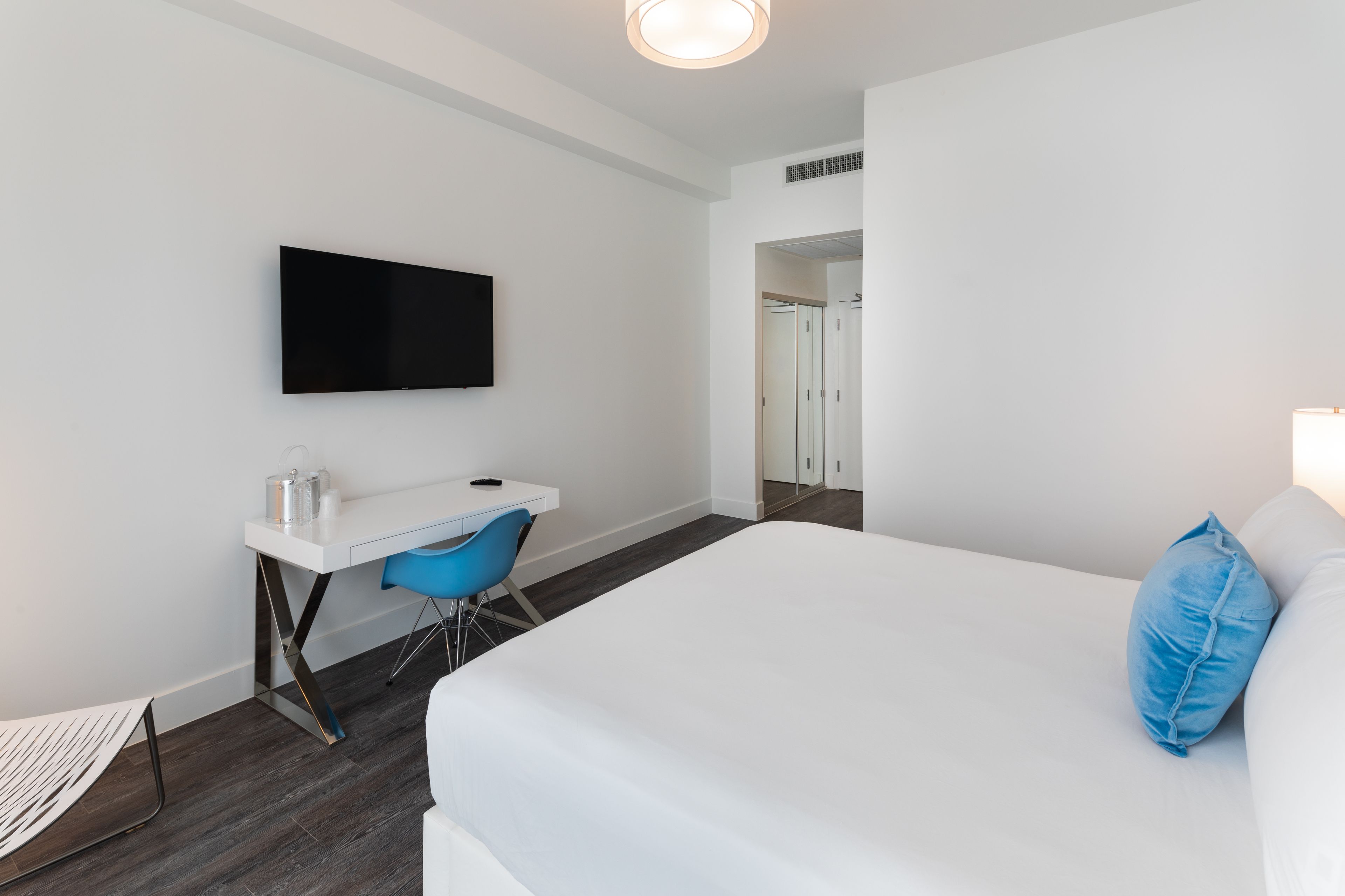 Une chambre d’hôtel moderne dotée d’un grand lit, d’un bureau avec une chaise, d’une télévision à écran plat et d’un dressing.