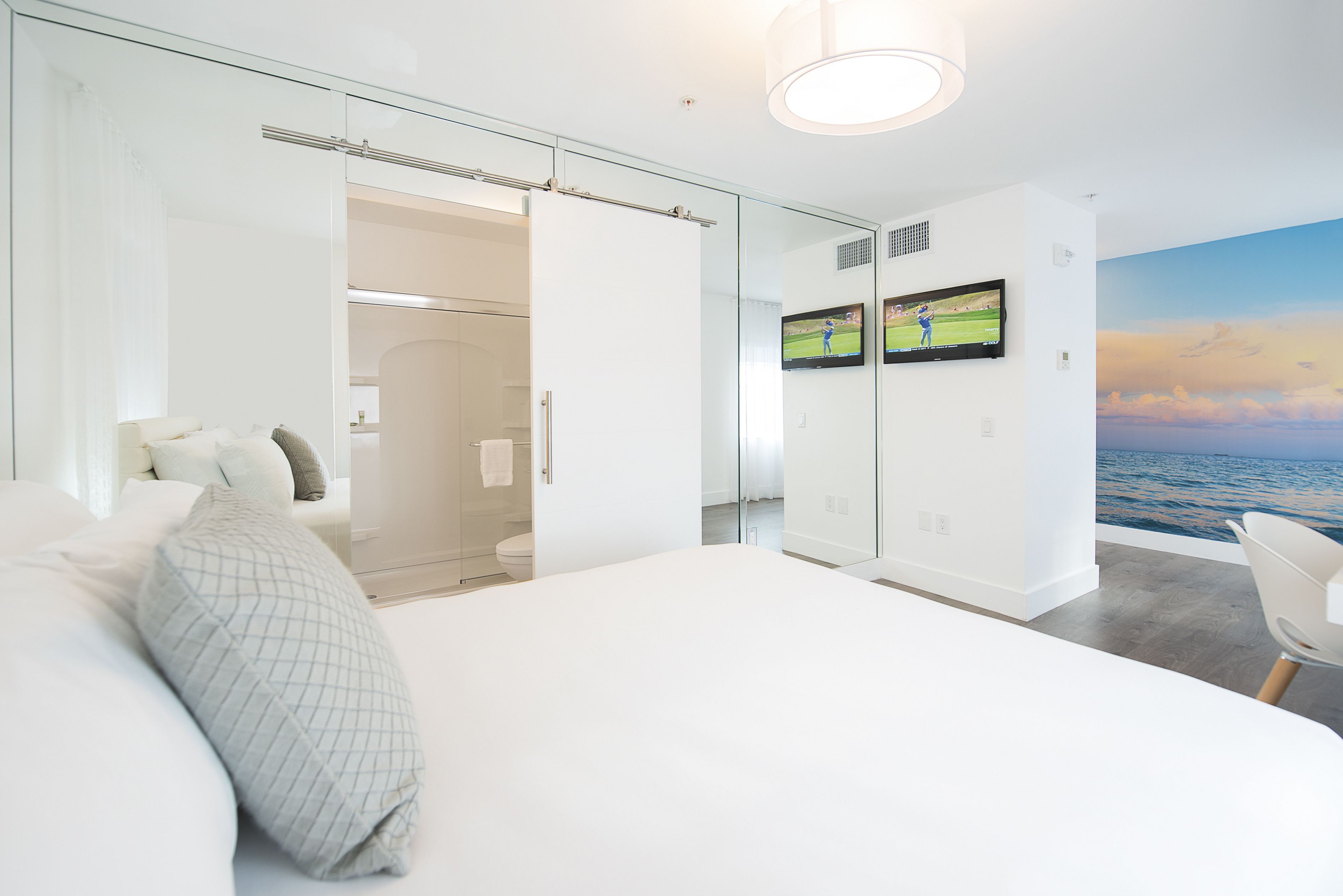 Un dormitorio moderno con una cama grande, un armario de vidrio y un televisor mostrando un partido de golf.