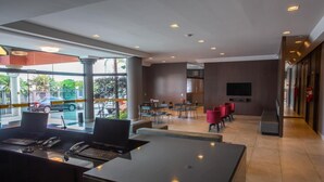 A modern hotel lobby with a reception desk, seating area, and a large window offering a view of the street. - Carlton Plaza Hotel Uberlândia (Uberlandia)