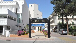 The entrance to the Morial Hotel with a clear pathway leading to the entrance, surrounded by potted plants and a blue awning.