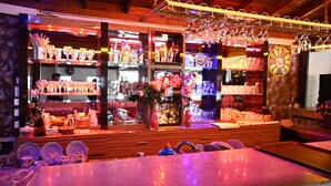 A bar area with shelves of bottles, glasses, and a clock on the wall.