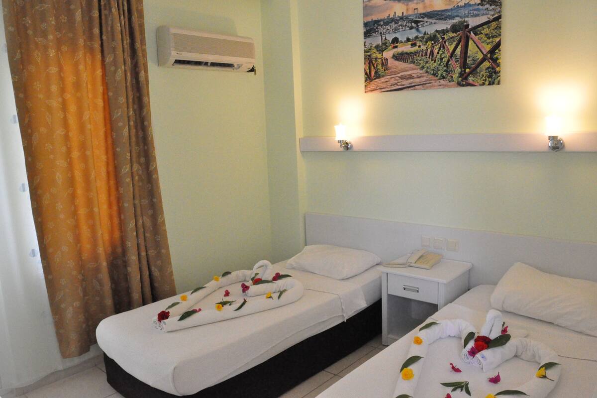 Una habitación de hotel con dos camas individuales, una mesita de noche con teléfono y un cuadro en la pared.
