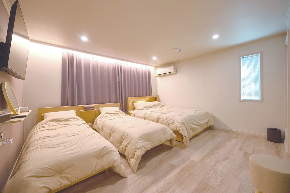 A bedroom with two beds, a mirror, an air conditioner, and a window.