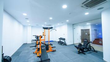 Une salle de sport équipée de machines d’exercice, d’un banc et d’haltères.