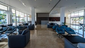 Eine großzügige Lobby mit modernen Sitzgelegenheiten, großen Fenstern und einer zentralen Säule.