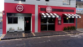 A building with a red facade, a Maraja Hotel sign, and a V. Teresa Cafe sign.