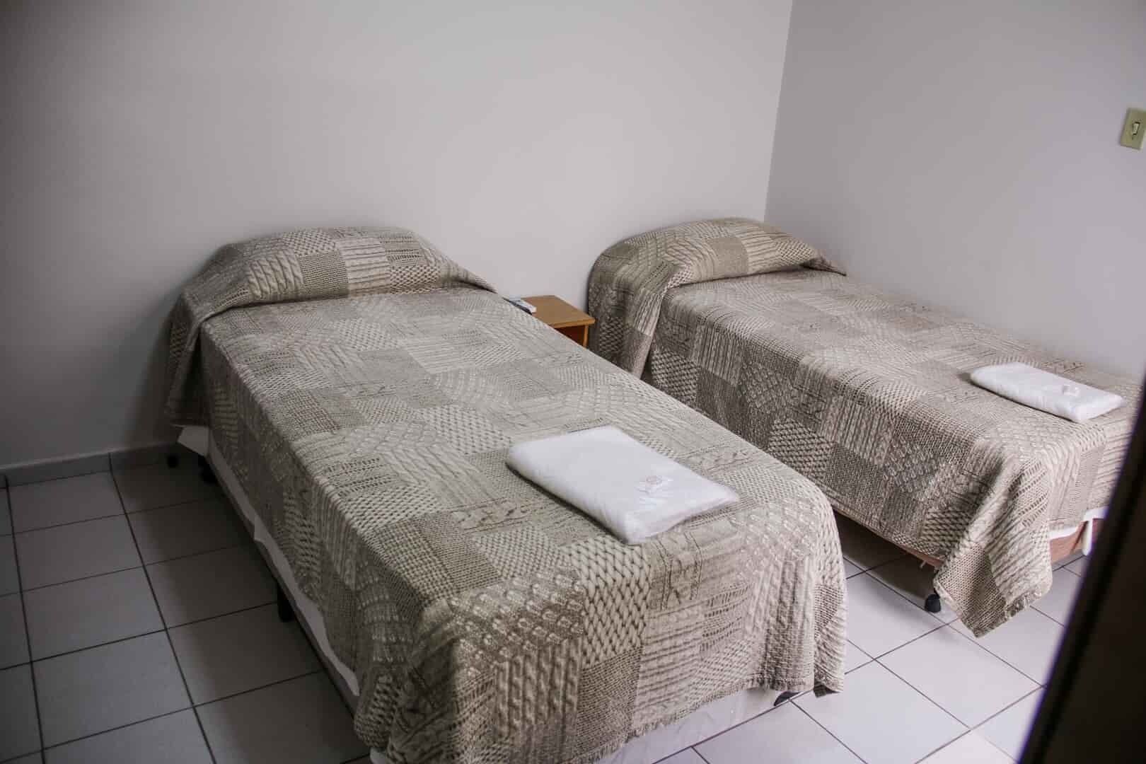 A room with two single beds, each with a patterned blanket and a pillow.