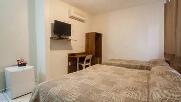 Un dormitorio con dos camas, un escritorio, una silla, un televisor y un refrigerador pequeño.
