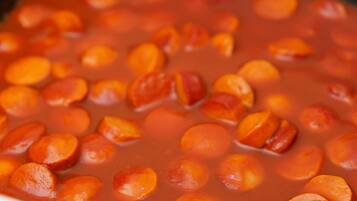 Un plato de cerámica blanca con salsa roja y rodajas de naranja.