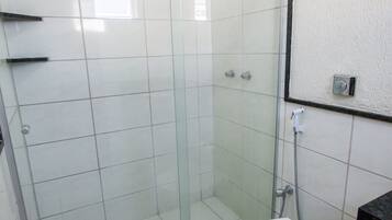 A bathroom with a glass-enclosed shower, a toilet, and a sink.