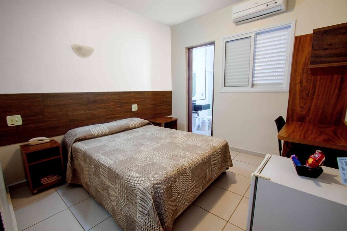 A bedroom with a bed, bedside table, and a small cabinet.