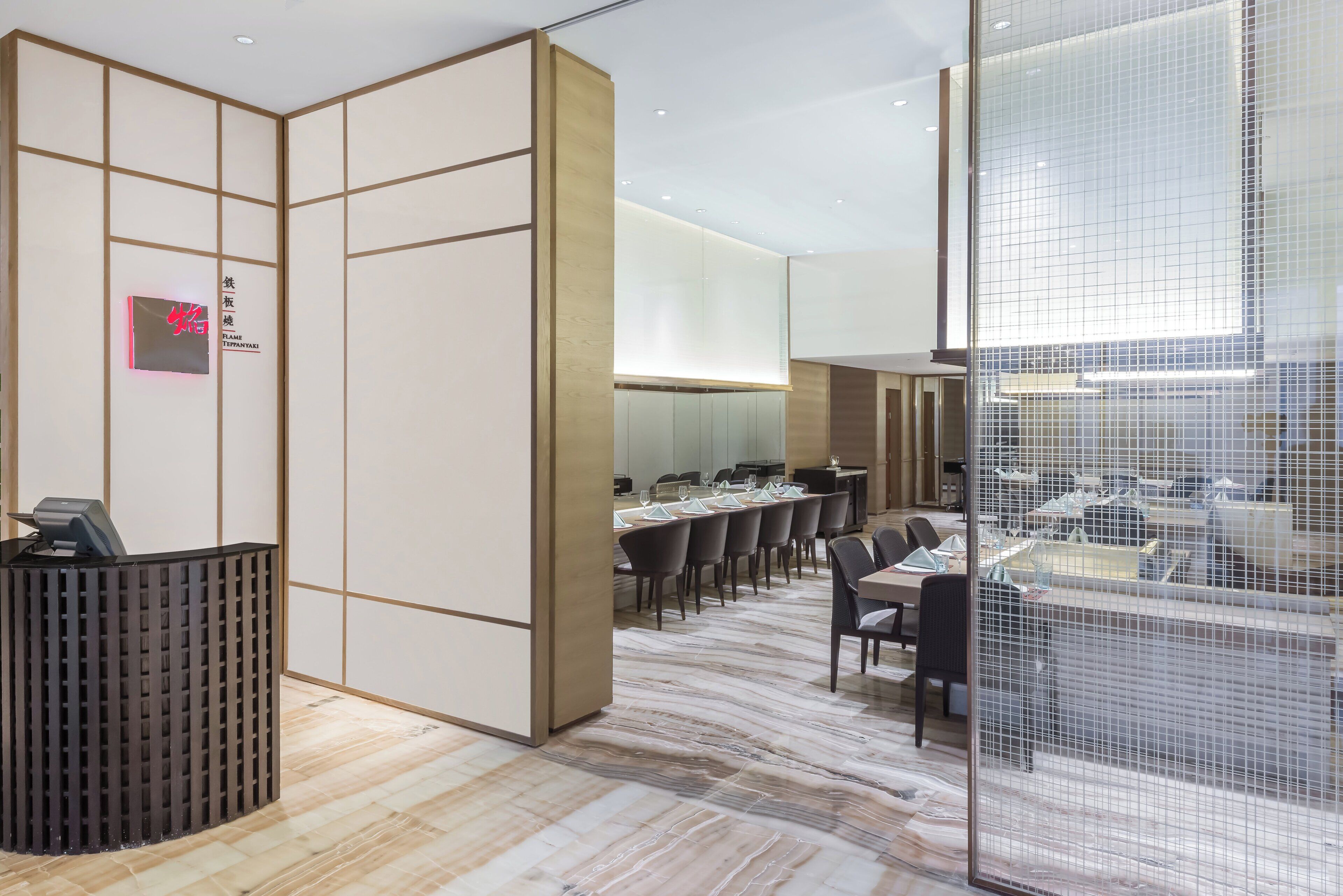 A modern hotel lobby with a reception desk, seating area, and a large window with a view.